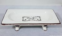 Top view of the white ceramic rectangular footed dish showing Paris themed decorative text and distressed brown rim.