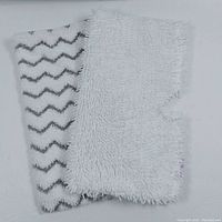Two new replacement pads for Shark steam mop showing white shaggy microfiber and zigzag pattern