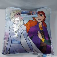 Cushion with printed design of Disney Frozen characters Anna and Elsa in packaging.