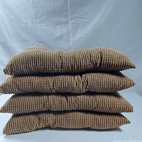 Stacked view of four brown corduroy fabric seat cushions, showing ribbed texture and thickness.
