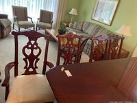 Four cherrywood dining chairs around a matching table in a living room, showing overall set with upholstered seats.