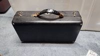 Closed black carrying case with leather handle and metal clasps for two clarinets.
