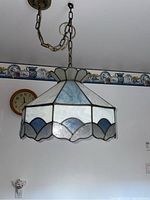 Overall angled view of the hanging Tiffany style light fixture showing stained glass panels and chain hanging from ceiling mount.