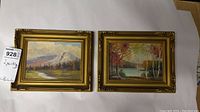 Two small framed original signed oil paintings shown side by side, highlighting the detailed gold-tone frames and the landscape artwork inside.
