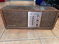 Front view of the RCA Victor radio showing woven fabric speakers, AM/FM frequency dial, knobs, and wooden casing.