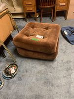 Brown vintage square tufted upholstered ottoman on carpeted floor, two images from slightly different angles.