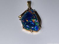 Front view of irregular triangular freeform opal doublet set in 14k gold prongs