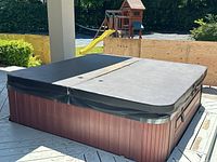 Closed cover view showing brown composite side panels and black vinyl cover from left side.