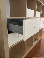 Close-up of open white drawer inserted into cube compartment showing metal knob and drawer interior