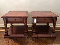 Front view of the pair of solid wood end tables showing drawer, legs, and lower shelf