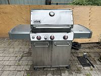 Front view of Weber Genesis grill showing lid, control panel, side shelves and cabinet