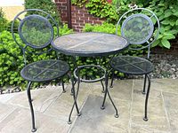 Front view of round mesh table and two chairs on patio
