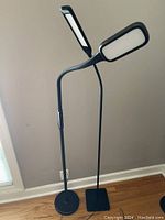 Both adjustable LED floor lamps standing side by side showing different base shapes and lighting heads