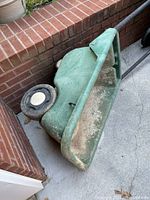 Green 3-wheeled hard plastic wheelbarrow showing basin and single wheel.