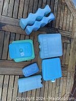 Various blue ice packs in different shapes and sizes arranged on wooden surface