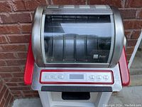 Frontal view of the Ronco Showtime Rotisserie Oven showing stainless steel and red accents with a glass door.