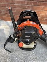 Front view showing engine, fuel tank, and blower intake with straps attached