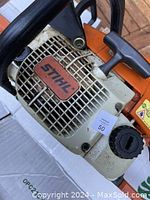 Close-up of the STIHL branded engine cover and fuel cap showing light wear and dirt.