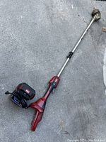 Full view of Toro cordless trimmer laid on ground showing battery mounted and shaft length.
