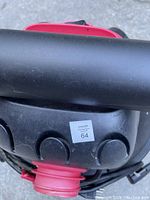 Front view showing hose connection and power cord wrapped around the vacuum body with a label sticker.