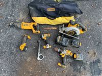 Full view of all items in the lot arranged on a cracked concrete ground showing tools and carrying bag