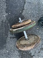 Adjustable dumbbell assembled with weights showing wear and rust on surface, handle and plates are clearly visible.