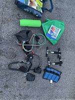 Wide view of the exercise equipment including resistance bands with pulley, ankle weights, push-up handles, green yoga mat, and inflatable stability ball with cover and guide.