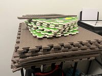 Stack of brown and designed foam floor mats showing thickness and interlocking edges