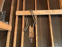 Four curved metal ladder supports hanging mounted on wooden rack in a workshop environment.