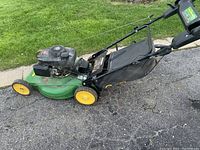 Side view of mower showing deck, wheels, handle and bag