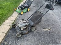 Full view of the used green and black Murray push lawn mower with grass bag attached and metal deck, positioned on driveway