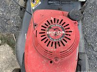 Top view of red Honda GCV 150 Easy-Start overhead cam engine mower, showing engine cover with some dirt and wear.