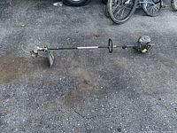 Full view of Craftsman string trimmer lying on ground showing entire unit with engine, shaft, handle, and cutting head with protective cover.