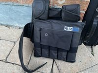 Front view of black Run Max weight vest with adjustable straps and pockets for weights on stone surface