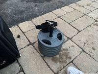 Stack of six 10 lb weight plates on the pavement showing their size and securing rod with attached handle.