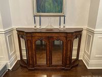 Front view of antique walnut veneer buffet with mirrored door panels and carved accents