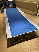 Full view of one blue and grey camp cot showing fabric and steel frame