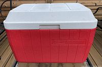 Front view of the red and white Coleman cooler showing the embossed logo and reversible lid.