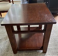 Side view of a dark brown wooden craftsman style side table showing lower shelf and sturdy square legs.