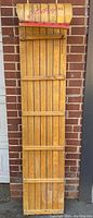 Full-length view of the vintage wooden toboggan showing the slatted blonde oak hardwood construction and structural supports.