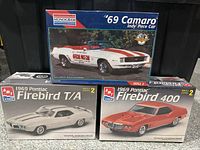 Box set of three sealed model kits: 1969 Pontiac Firebird T/A, Firebird 400 by AMT and '69 Camaro Indy Pace Car by Monogram shown stacked.