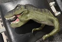 Full side view of the green Jurassic Park T-Rex puppet showing detailed skin texture, open mouth, teeth, and eye details