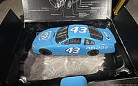 Top-down view of blue Richard Petty #43 Dodge diecast car inside black plastic molded tray with protective tissue.