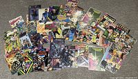 Top-down photo showing a spread of 53 assorted comic books from various titles on a gray carpet. Covers visible include superhero and sci-fi themes with multiple characters and colorful artwork.