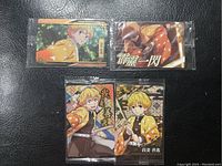 Four Japanese anime trading cards featuring Zenitsu Agatsuma from Demon Slayer, arranged on a black surface, each sealed in plastic.