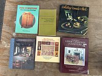 Lot of six reference books on antique furniture and Canadian history, books laid flat on wooden surface.