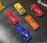 Five Hot Wheels G-Force Camaro diecast model cars of different colors displayed on black surface.