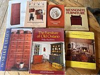Photo showing seven antique furniture reference books arranged on a surface, covers visible, titles mostly clear.