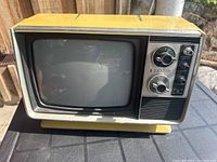 Full view of the yellow Zenith vintage 9-inch black and white TV on a table, showing front and top sides.