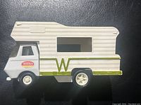 Side view of vintage Tonka camper toy showing white and green camper body with window and Tonka logo on cab door.
